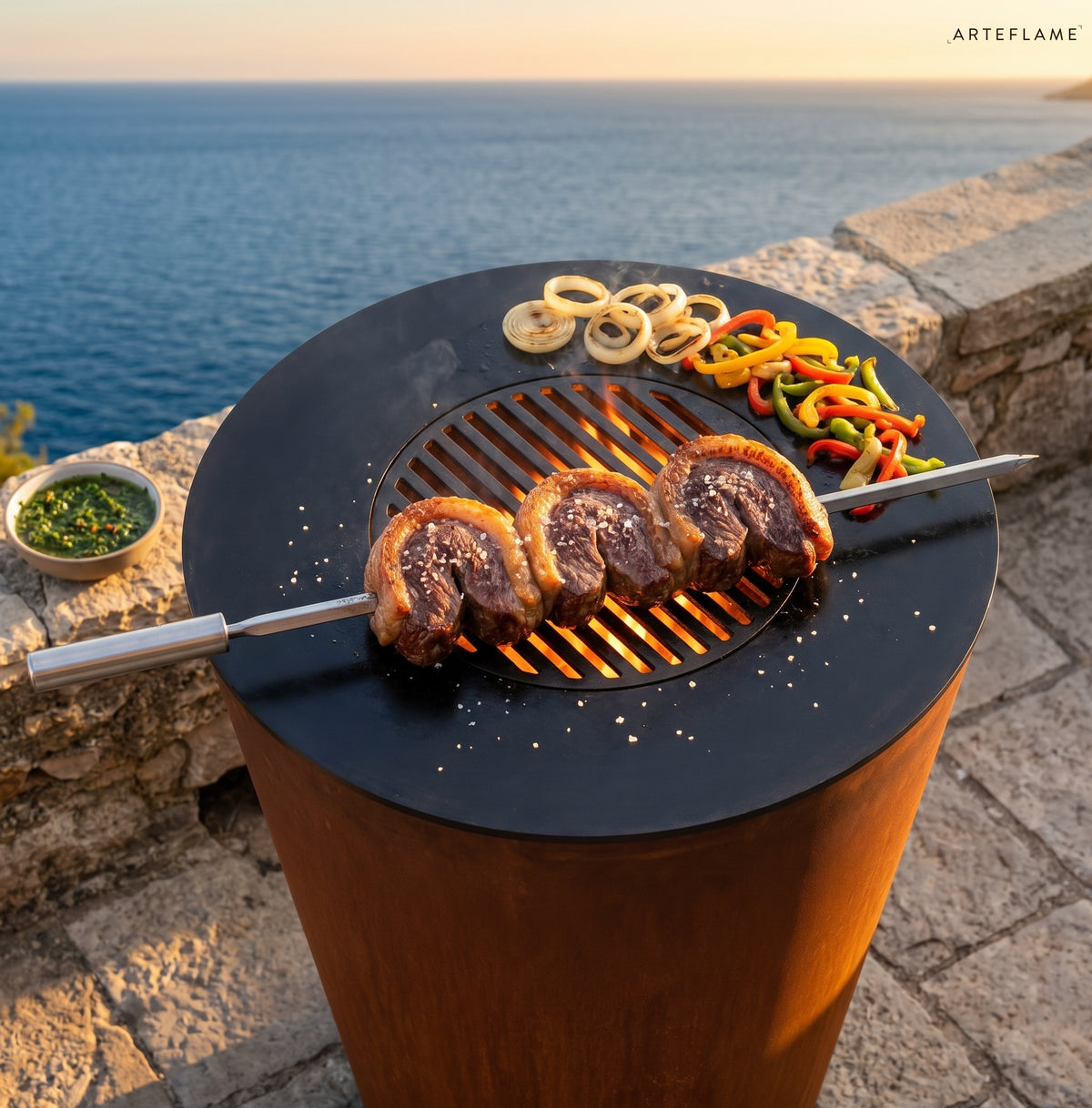Picanha steaks on a skewer grilling on an Arteflame grill by the sea