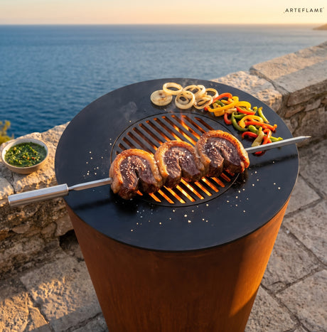 Picanha steaks on a skewer grilling on an Arteflame grill by the sea
