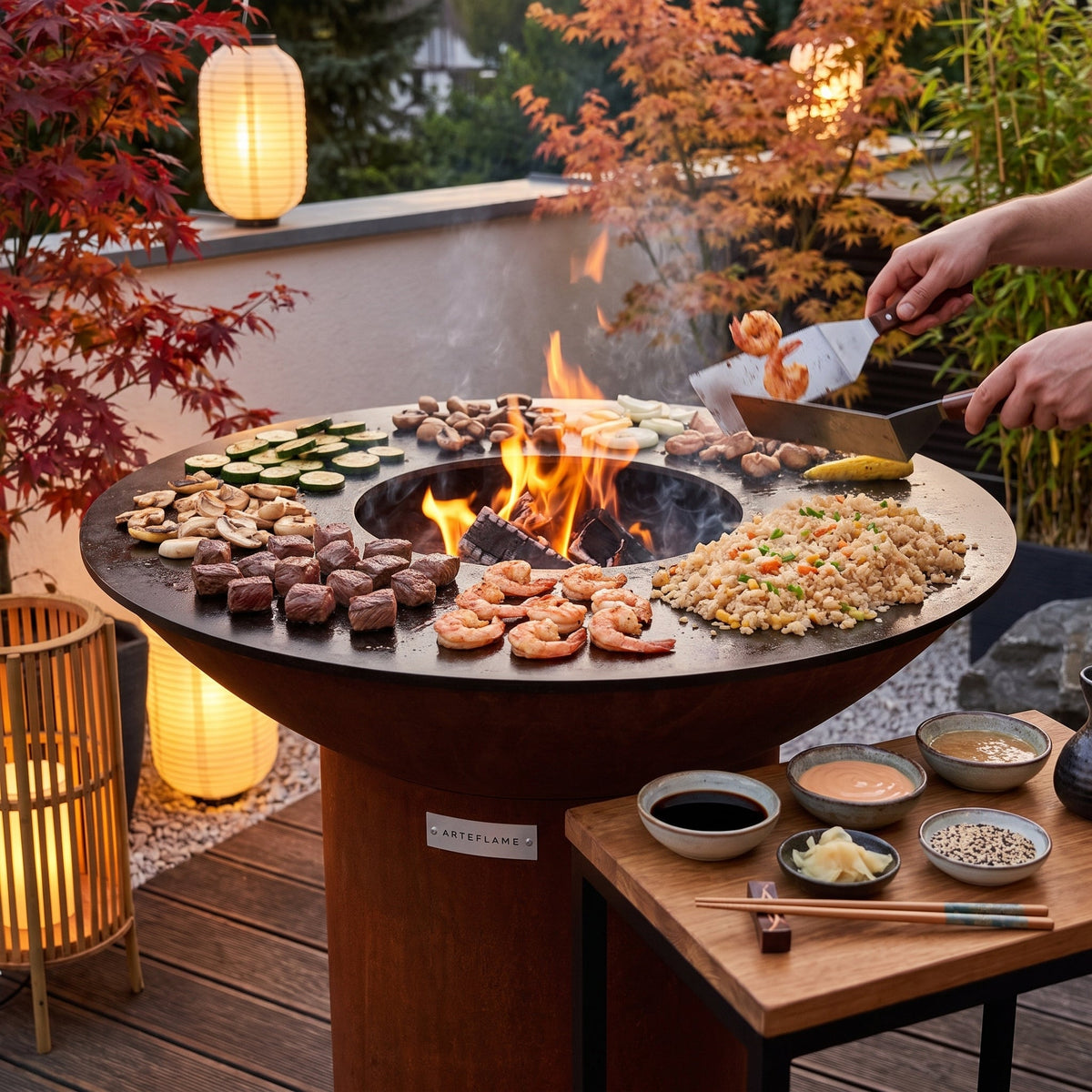 Hibachi-style steak, shrimp, vegetables and fried rice cooking on an Arteflame flat-top grill with a round Corten steel base in a Japanese garden