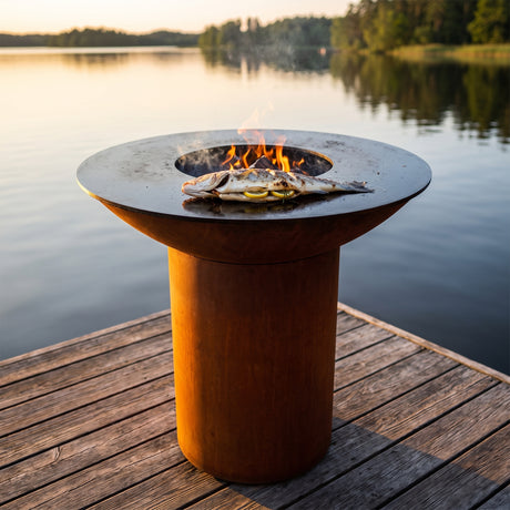 Whole branzino stuffed with lemon and herbs on an Arteflame wood-fired flat-top grill with a round Corten steel base