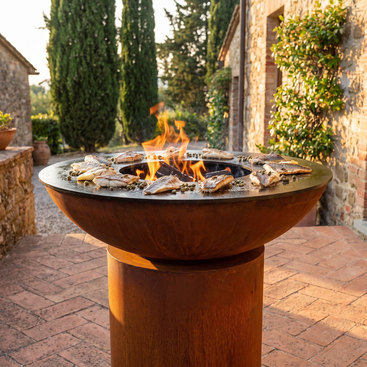 Skin-on fish fillets with crispy skin on an Arteflame wood-fired flat-top grill with a round Corten steel base