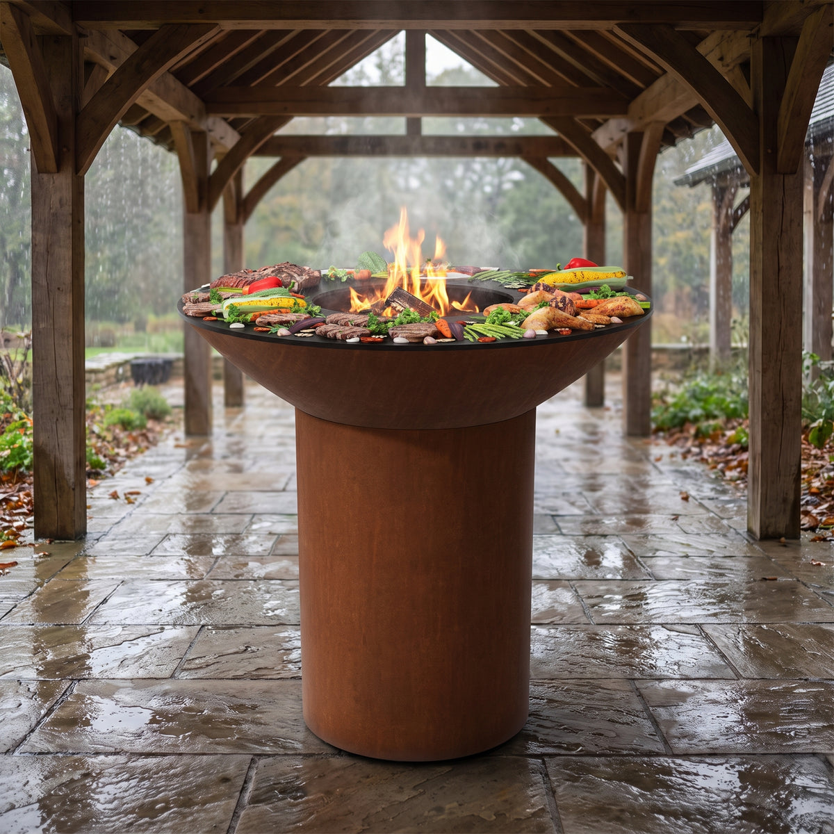 Grilling safely under a pergola in the rain on an Arteflame wood-fired flat-top grill with a round Corten steel base