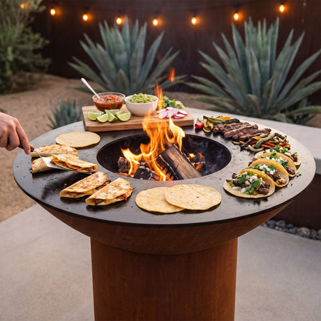 Quesadillas, tortillas, carne asada and street tacos cooking on an Arteflame flat-top grill with a round Corten steel base and wood fire