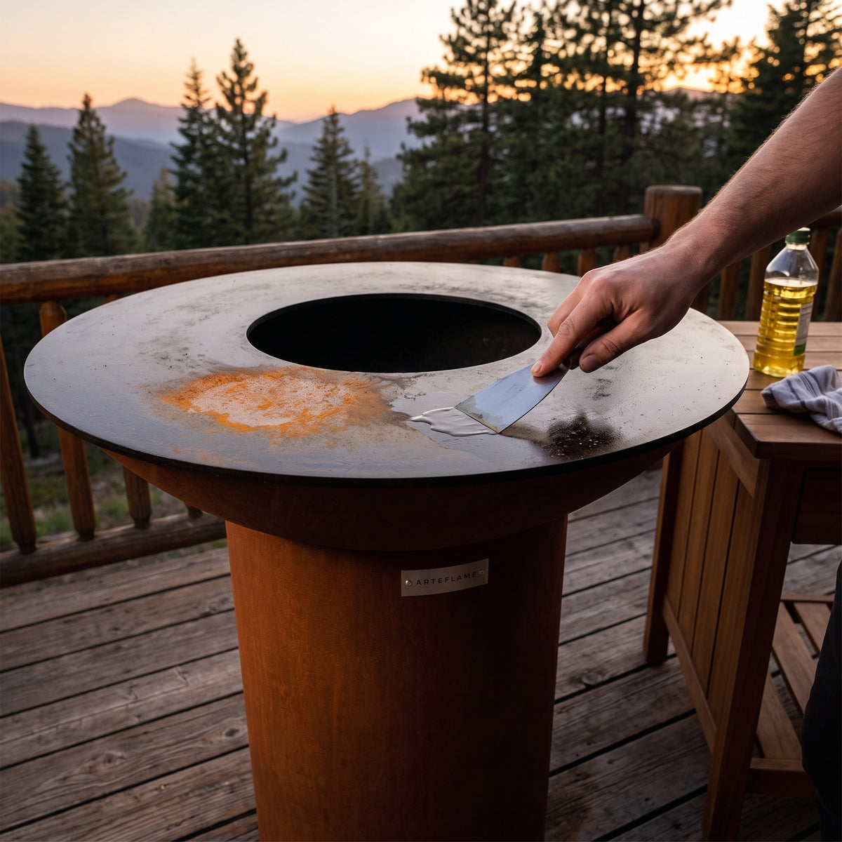 Removing light surface rust from the hot-rolled steel cooktop of an Arteflame wood-fired flat-top grill with a round Corten steel base