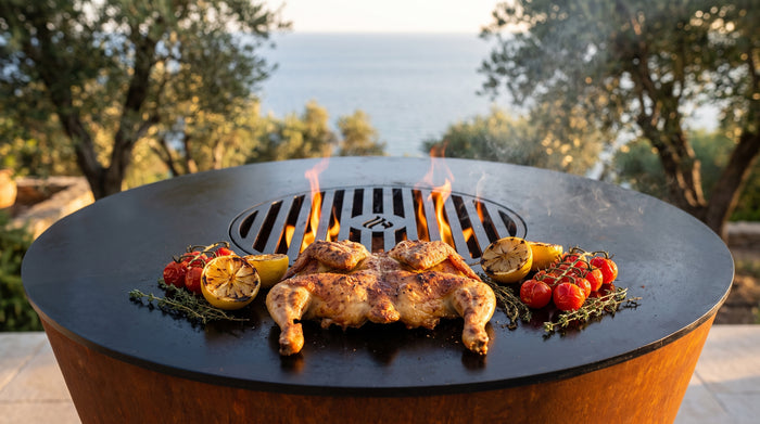 Spatchcocked chicken with charred lemons, cherry tomatoes and thyme on the Arteflame ONE30 cooktop beside the wood fire