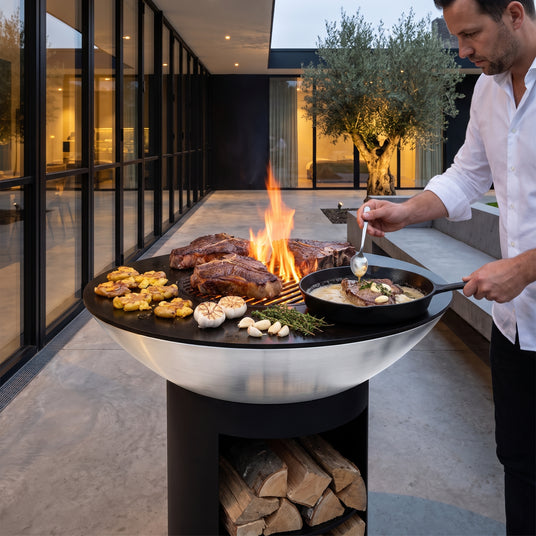 Porterhouse steaks searing on the Arteflame 40-inch Platinum Series stainless steel grill with storage base at dusk