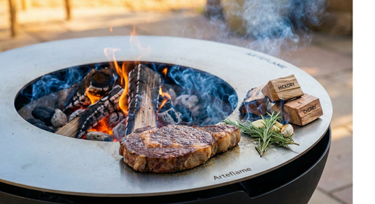 Steaks being cooked over an open flame on a portable fire pit with 'Arteflame' branding.